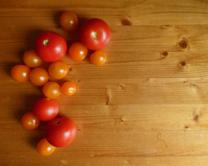 Red ripe tomatoes and cherry at the wooden table.