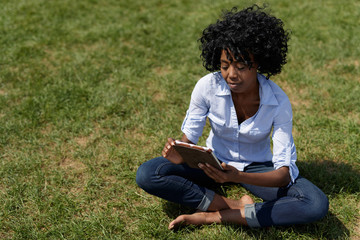 Black woman in a park using tablet computer
