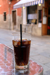 Tall glass of soda in an Italian cafe outdoor. Selective focus.