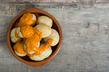 Canarian potatoes (papas arrugadas) with mojo sauce on wooden table

