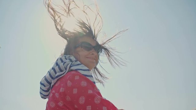 Happy woman in a cabriolet with high speed winds fanning her hair against the sun.