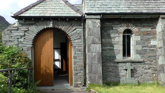 Small Christian church built of stones with slate stone roof with open door in rural England, UK