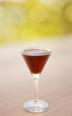 Glass of liquor on wooden table outdoors closeup