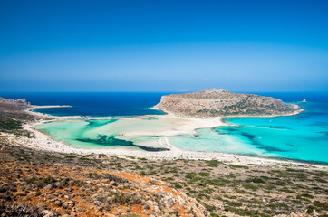 Fototapeta na wymiar Balos lagoon on Crete island, Greece. Tourists relax and bath in crystal clear water of Balos beach.