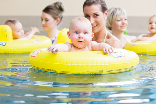 Mamas und ihre Babys haben Spaß mit Spielzeug beim Säuglingsschwimmen