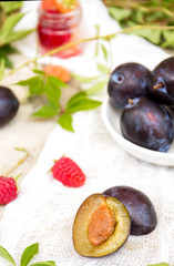 Fresh plum, raspberry, grape leaves on a concrete background
