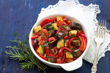 Ratatouille, a traditional French dish of vegetables in a white ceramic bowl on a dark blue background