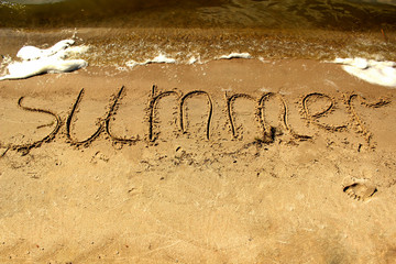 Inscription summer on the sand by the sea with waves