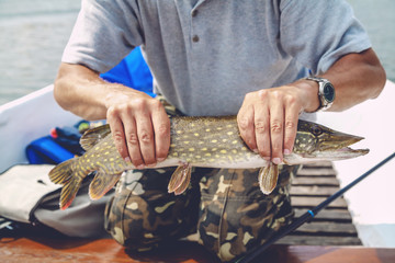 fisherman in boat holding pike