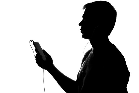 Silhouette of a young man with a smartphone with headphones