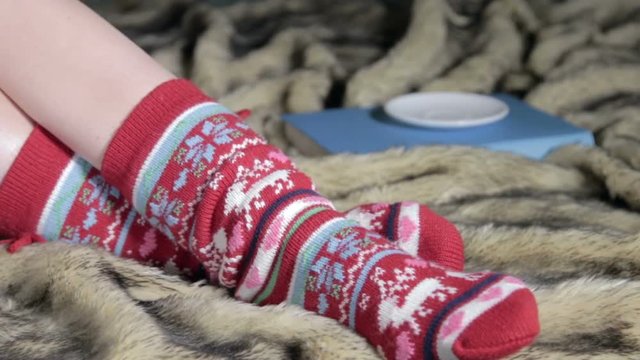 female legs in Christmas socks with a book