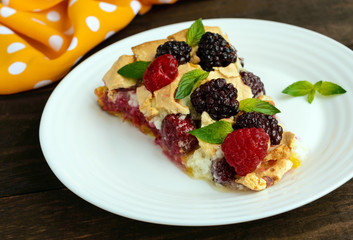 A piece of the pie (Tart) with fresh blackberries and raspberries, air meringue, mint decoration on a white plate