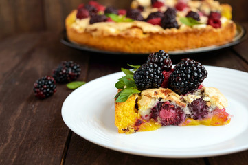 A piece of the pie (Tart) with fresh blackberries and raspberries, air meringue, mint decoration on a white plate