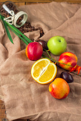 Still life on sackcloth background: apple, peaches, orance, plum