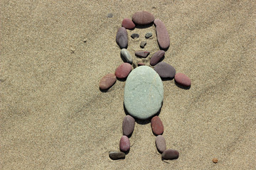 Pebble man on a sand background