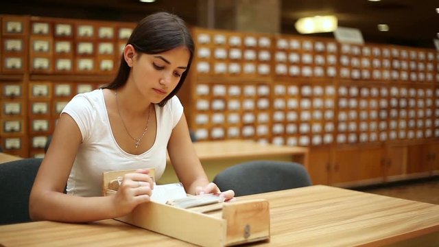 pretty girl looking on catalog on the table in a library