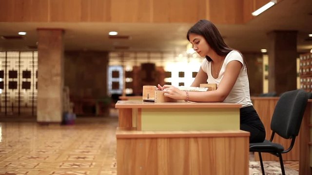 pretty girl looking on catalog on the table in a library