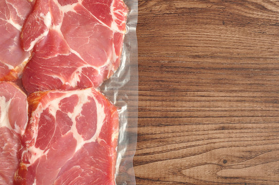 Vacuum Packed Meat Displayed On A Wooden Background