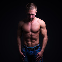 sport concept - handsome muscular man posing over dark backgroun