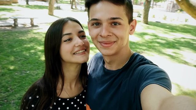 young boy and girl doing selfie on camera in the park, slow motion