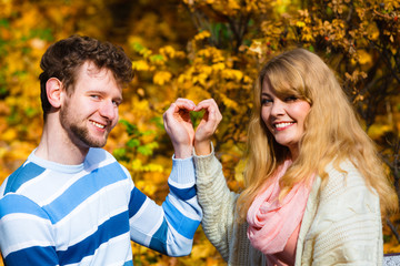 Obraz premium Young lovers in autumnal park make heart gesture.