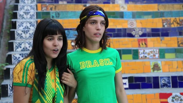 Two female Brazilian soccer fans celebrate while watching the game