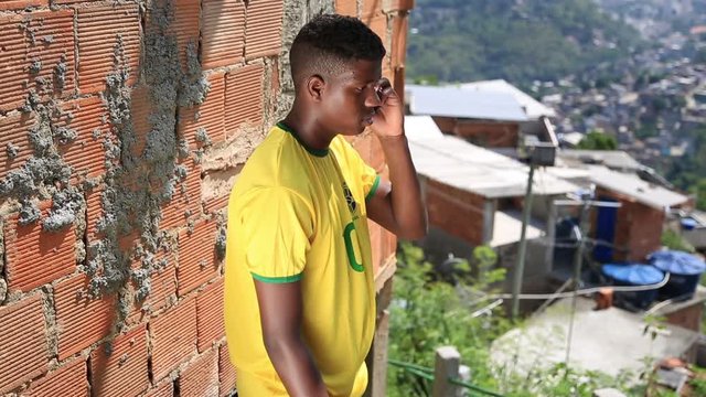 A kid talks on his cell phone while standing outside