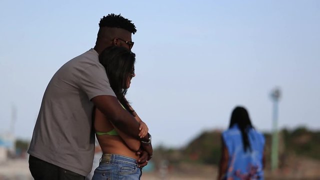 A young couple hold each other as they stand by the beach