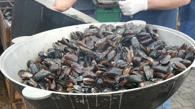 Chef cooking mussels on the street, slow motion