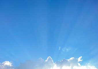Blue sky with clouds and light shining through.
