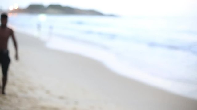 A man walks down the beach and stops to smile into the camera