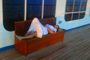 Bench Relaxing/Women in a white dress laying on a bench. 