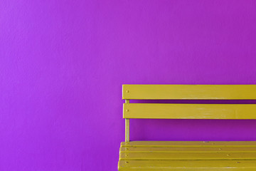 yellow wood bench on vivid violet wall background