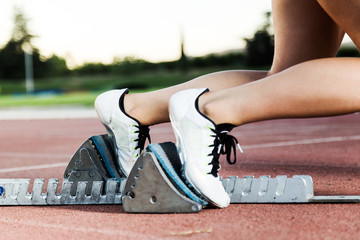 Young female athlete launching off the start line in a race.