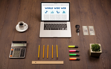 Laptop on wooden desk with office suplies