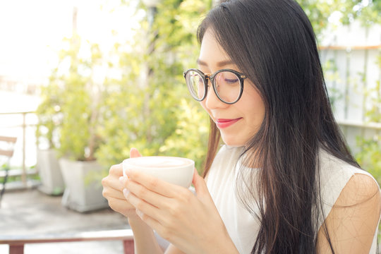 Close up of a woman taking in smell of coffee at morning in the garden.