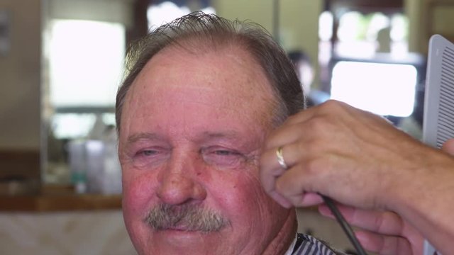 Closeup of elderly man getting haircut