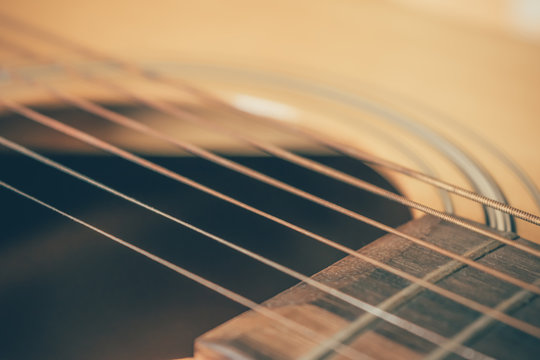 closeup picture of an acoustic guitar in a film tone, vintage style