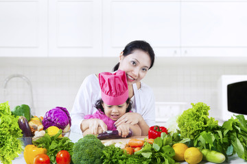 Child and her mother cutting vegetables