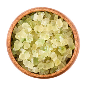 Diced green colored succade in a wooden bowl on white background. Candied peel of the citron fruit, Citrus medica, often used in cakes as a filling. Food. Isolated macro photo close up from above.