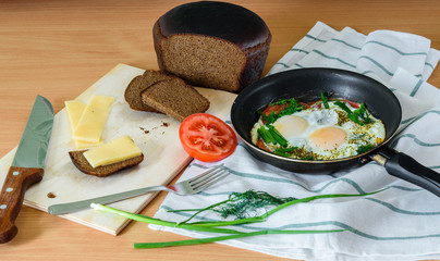 fried eggs with herbs and tomatoes in a pan.