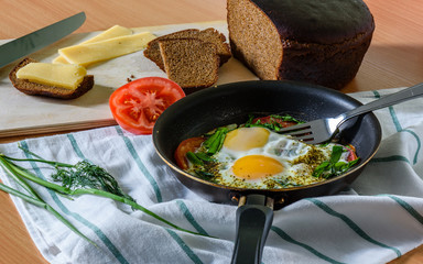 fried eggs with herbs and tomatoes in a pan.