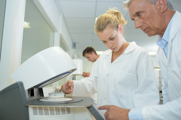 Male and female technicians using machine in laboratory