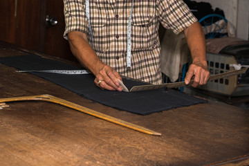 Tailor at work, drawing line on fabric with chalk
