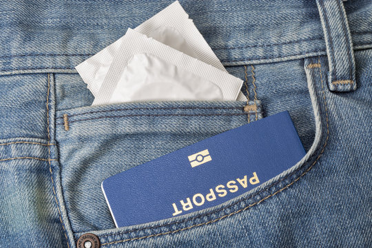 Condoms and passport in the pocket of blue jeans closeup