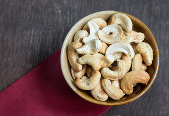 Bowl of cashew nuts from above. On wood background.