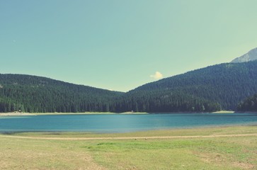 Idyllic lake landscape in the mountains on a sunny day; green fields and blue water; nature. Image filtered in faded, nostalgic, retro, Instagram style. Black lake, Durmitor, Montenegro. - 119206213