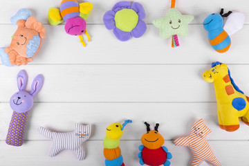 colorful soft baby toys on wooden background with copy space