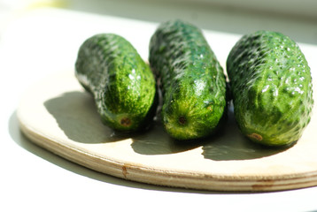 Три зеленых свежих огурца на деревянной кухонной доске