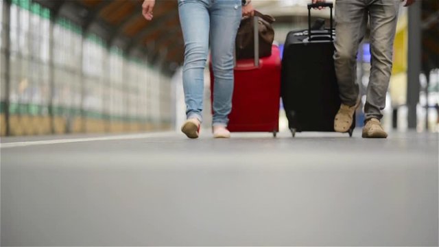 Feet walking on the platform passengers with a suitcase, young couple walking along the platform to the train with baggage